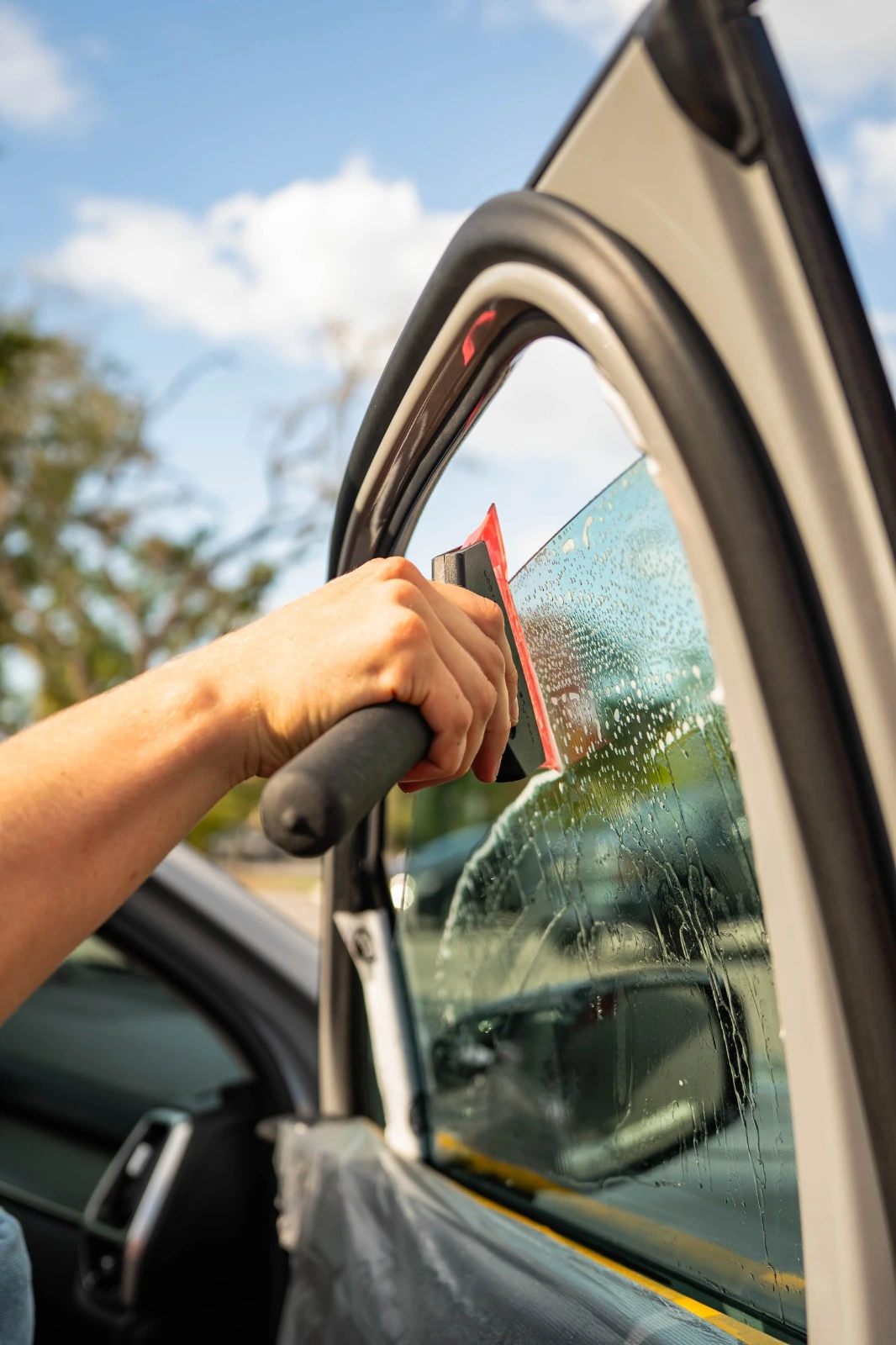 Professional window tinting service with squeegee tool